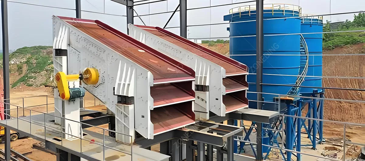 A large, multi-deck vibrating screen separating crushed stone into different size stockpiles at a quarry